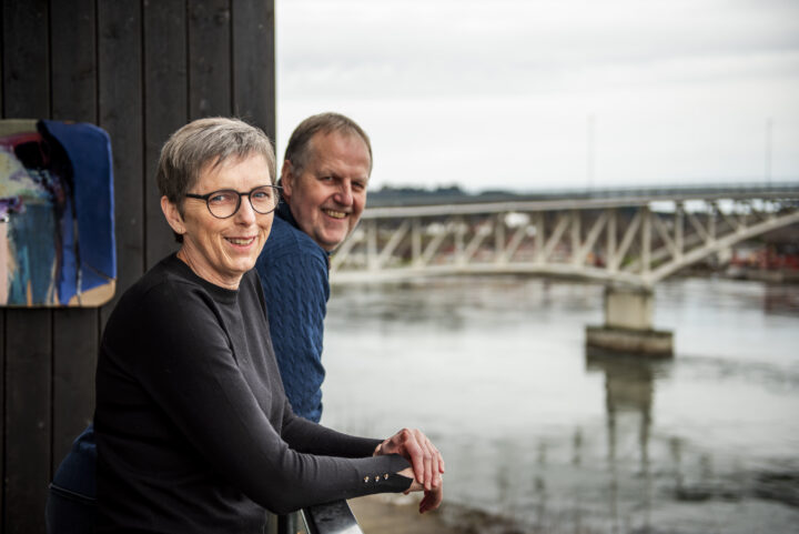 Smilende mann og kvinne med en bro over fjorden i bakgrunnen