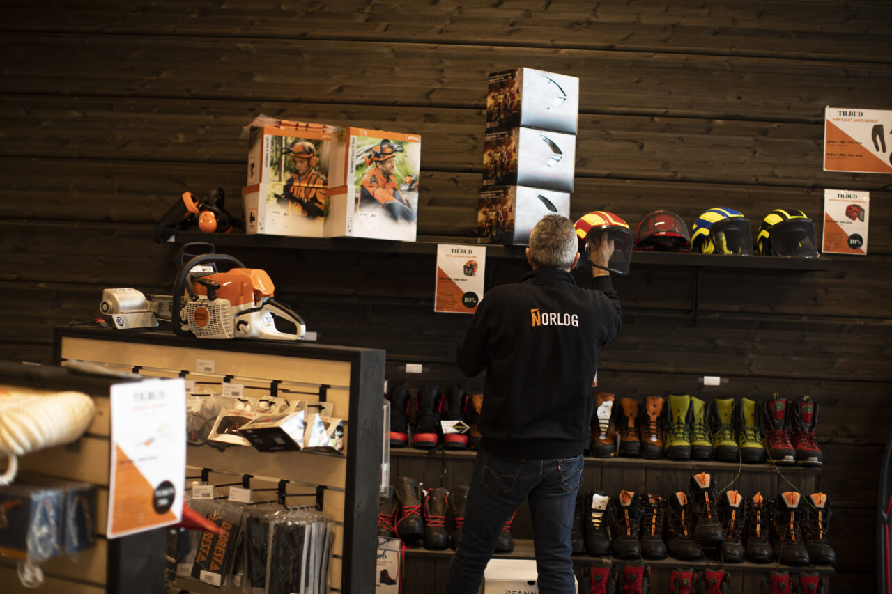 mann stor med ryggen til i en butikk som selger skogbruksutstyr