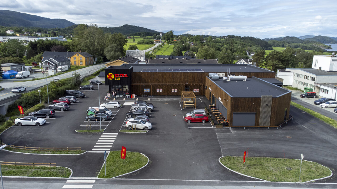 brunt butikklokale med biler på parkeringsplassen foran