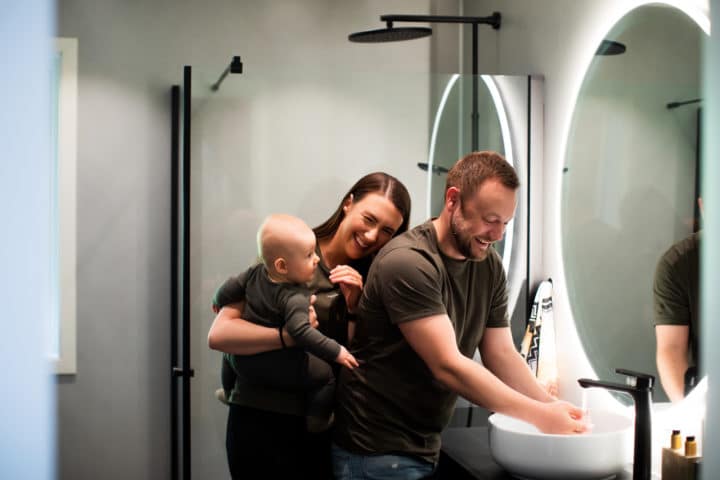 Mor, far og baby foran et rundt speil