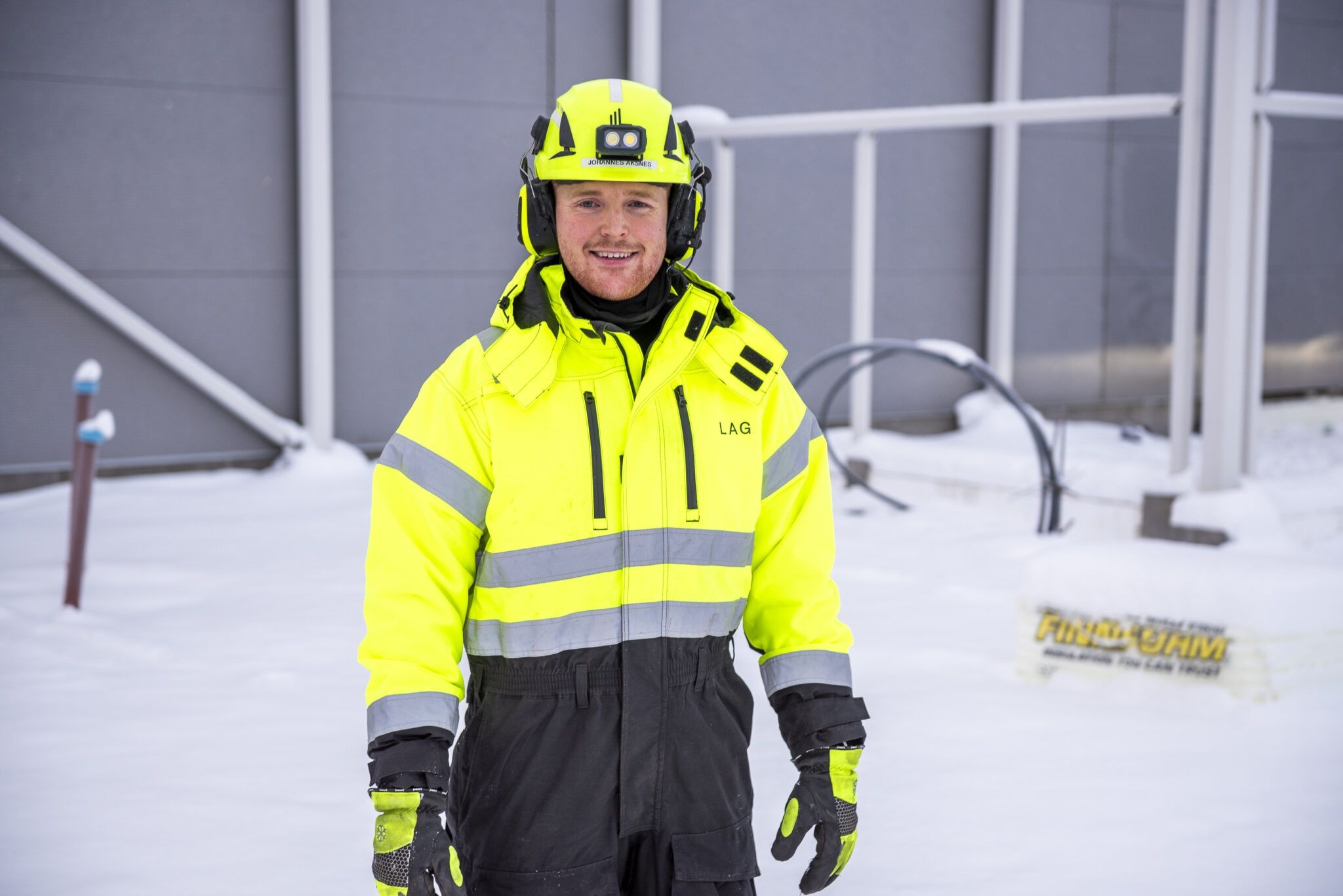 Smilende mann i arbeidsklær ute i snøen