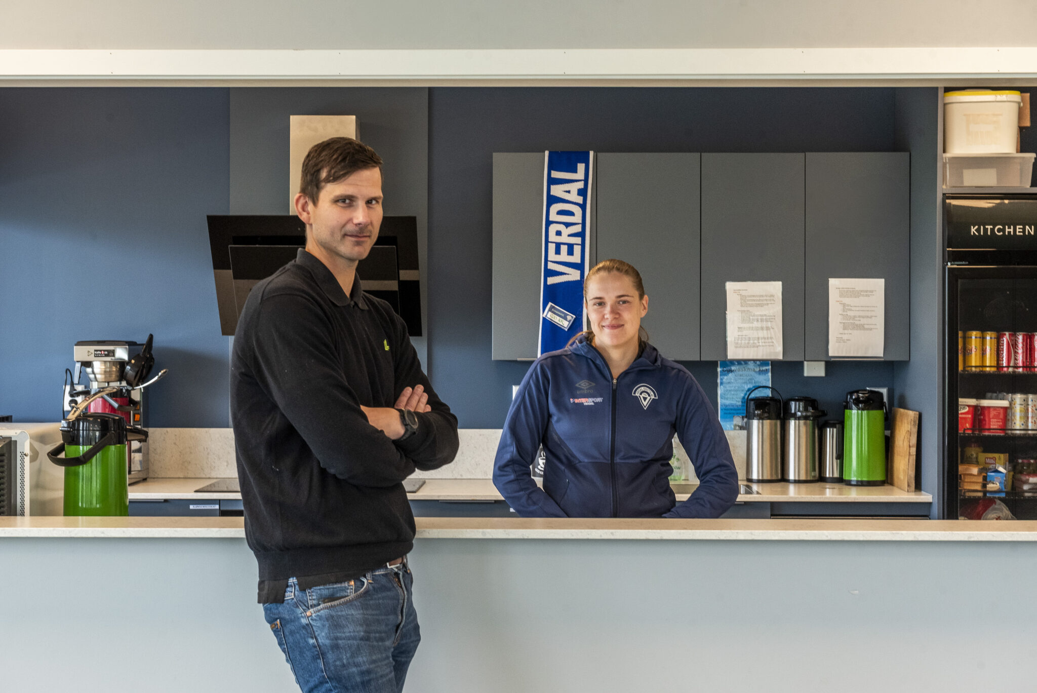 Mann står foran en kioskbenk og en kvinne bak.