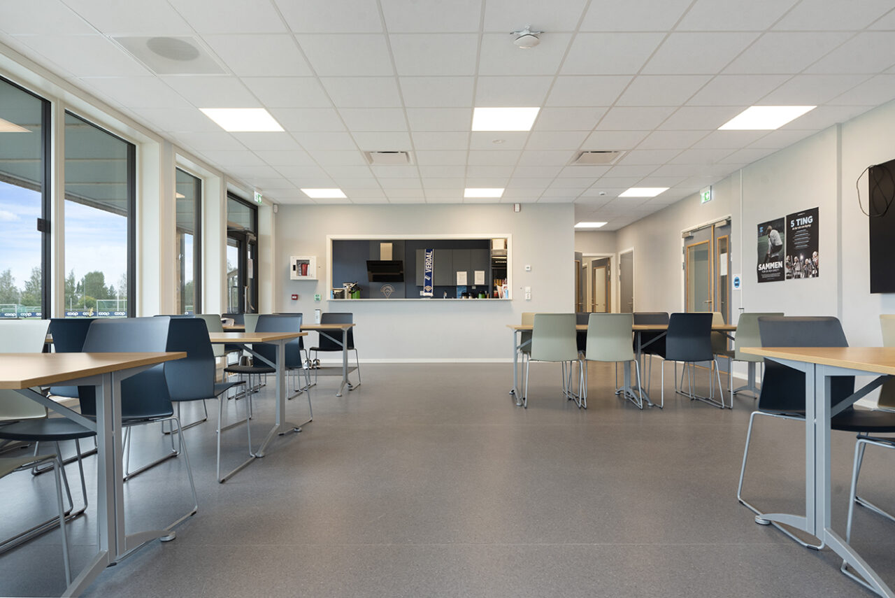 stort åpent rom med kjøkkendisk i den ene enden og bord og stoler på sidene